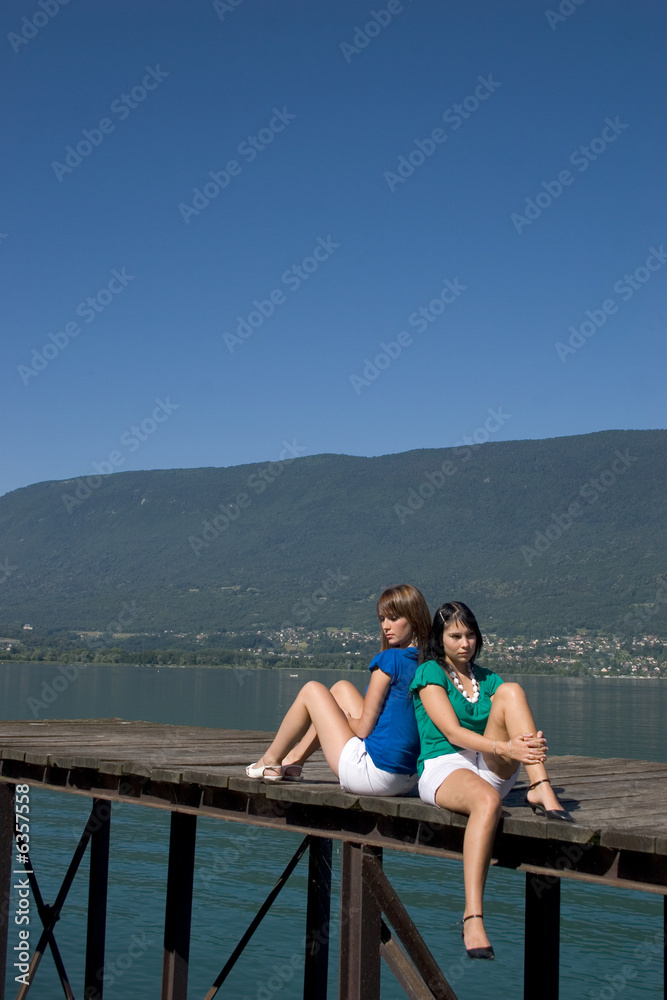 young woman sitting on a pontoon at the edge of a lake