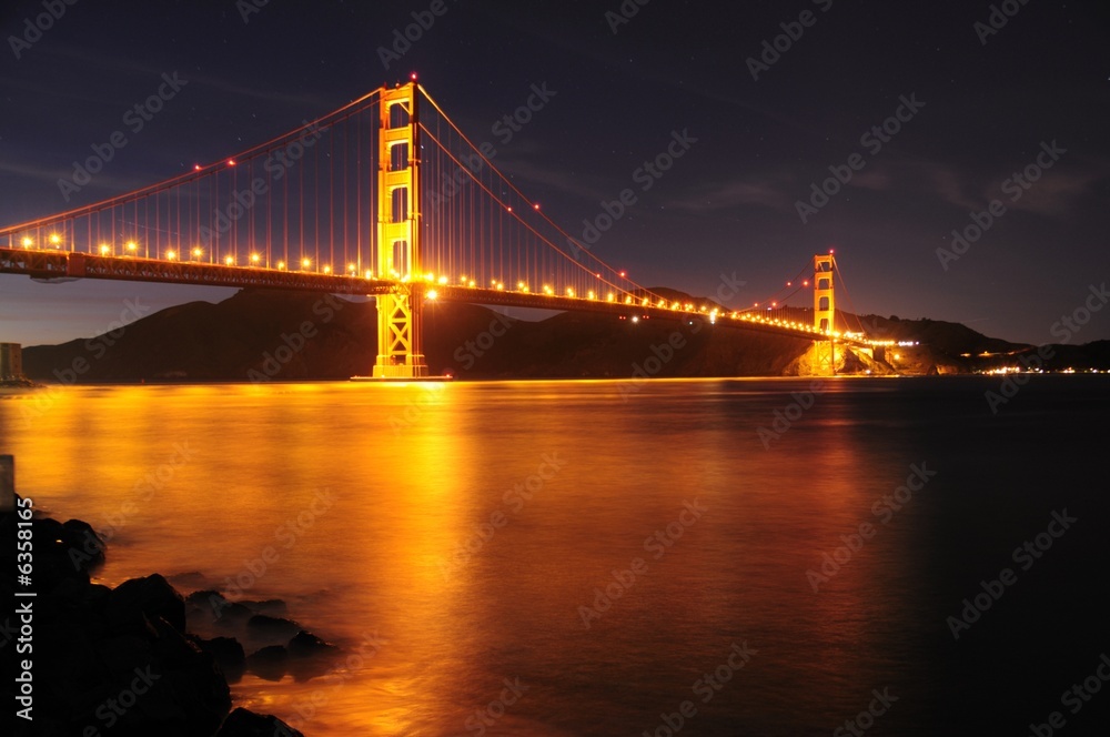 Glowing Golden Gate Bridge and star trails behind