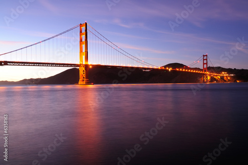 Fototapeta Naklejka Na Ścianę i Meble -  Glowing Golden Gate Bridge at sunset. Shot from Fort Point area.