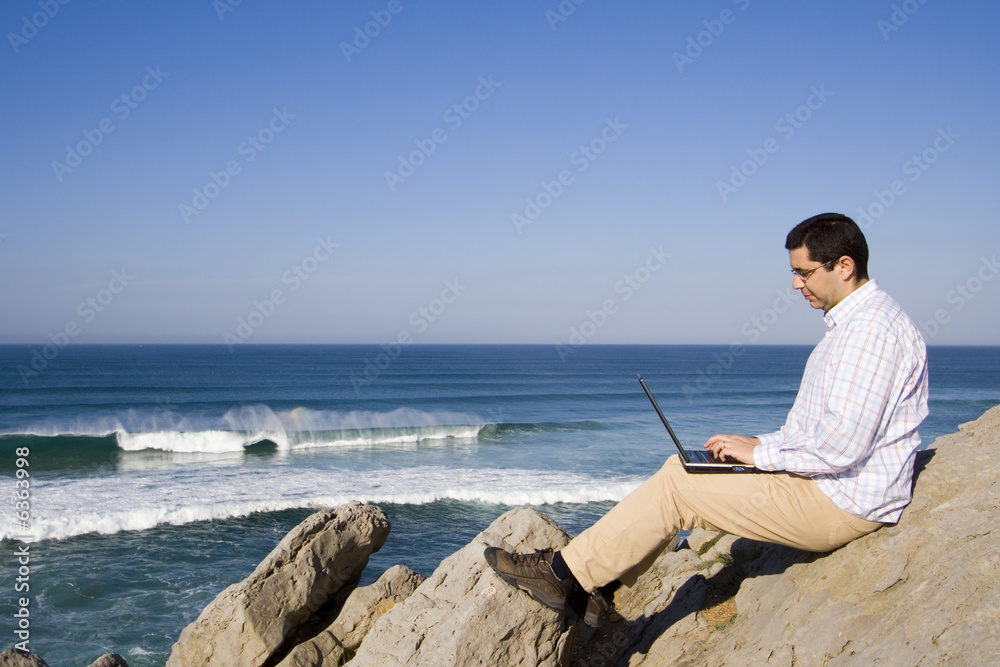 young man working with the laptop at the beach