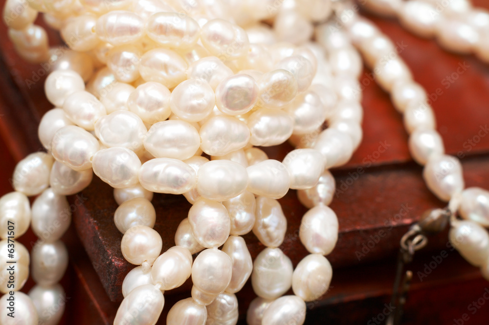 String of white real river pearls on brown wooden box String of white real river pearls on brown wooden box