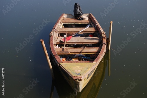 Old wooden boat beside pier with  oar .