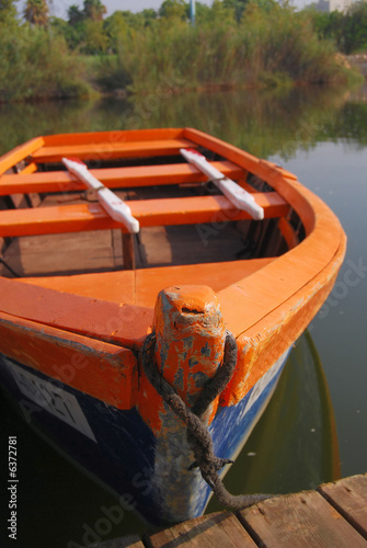 old wooden boat beside pier with two white oar