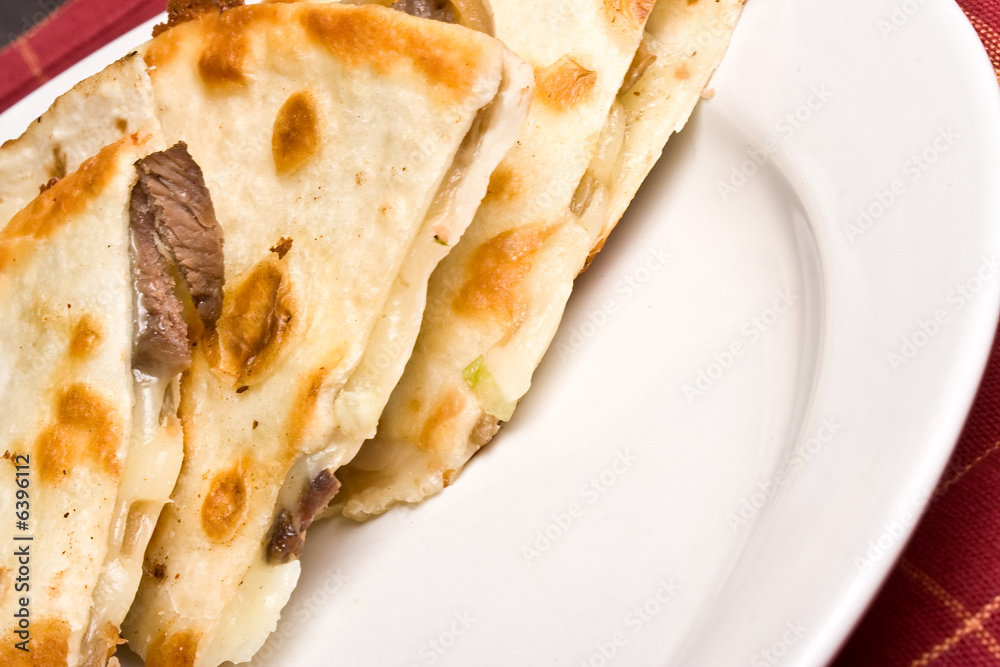 fresh off the stove a steak Quesadilla on a white plate