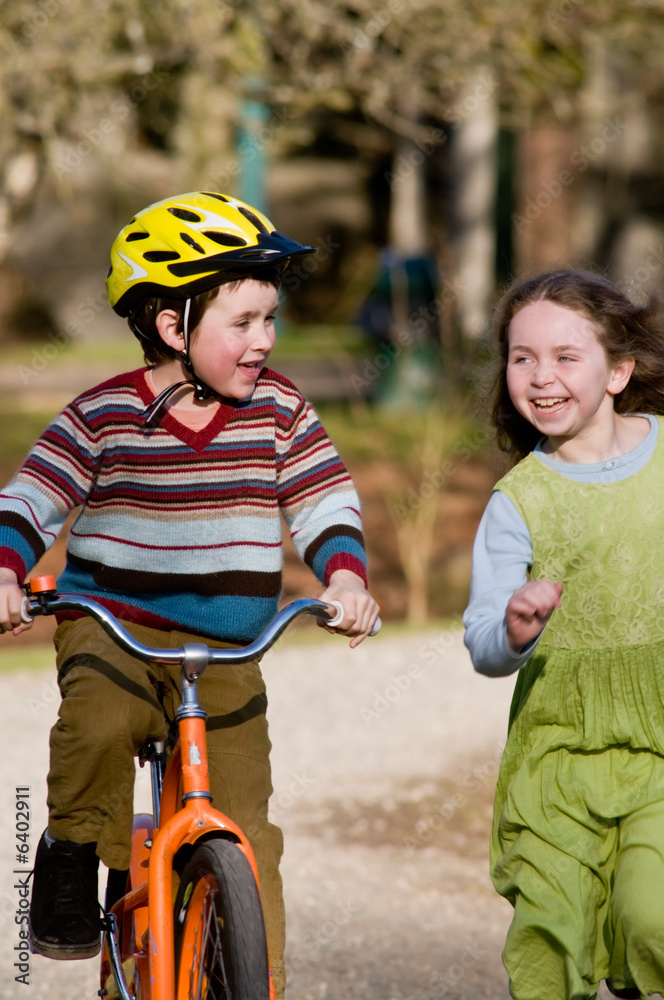 Obraz premium boy on bike, girl running beside him