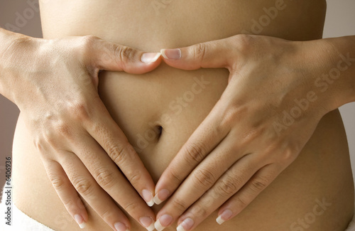 Hand on belly with heart shaped fingers