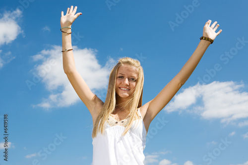 Enthusiastic young teen girl raising her arms in celebration 