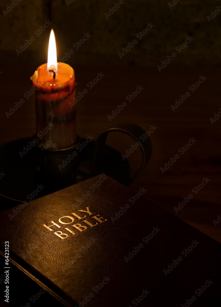 Obraz premium Nastrojowy obraz Biblii obok świecy.