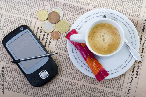 Cellphone, money and coffee over newspaper -business concept