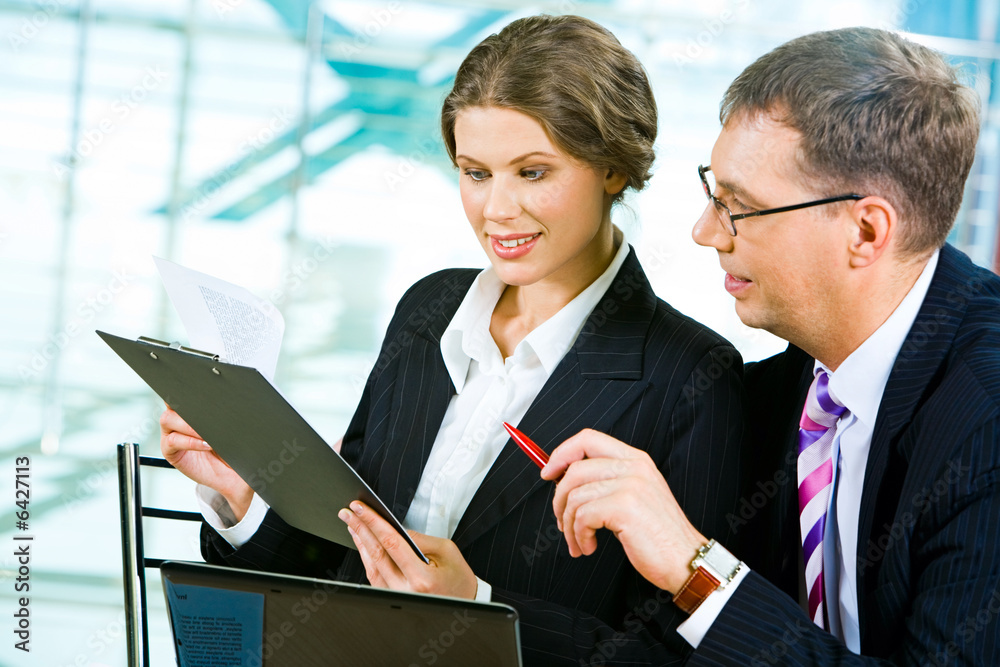 Portrait of two colleagues looking into business plan Portrait of two colleagues looking into business plan