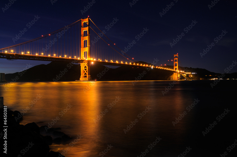 Golden Gate Bridge with star trails in the sky behind it