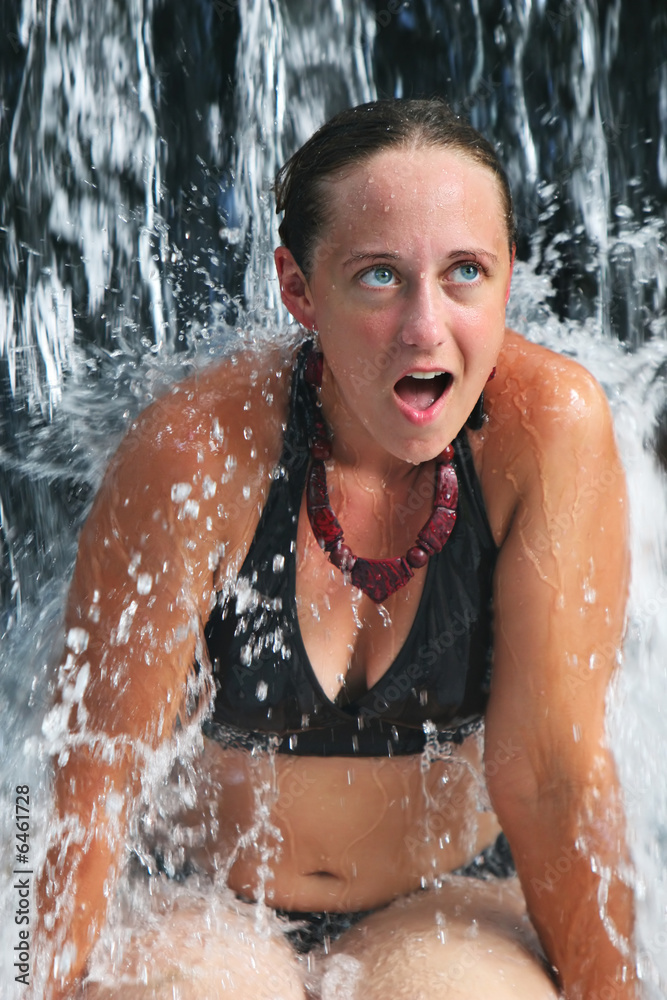 Obraz premium A young woman under a waterfall at a luxury resort in Costa Rica