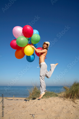 girl with colorful balloons jumping on the beach © bereta