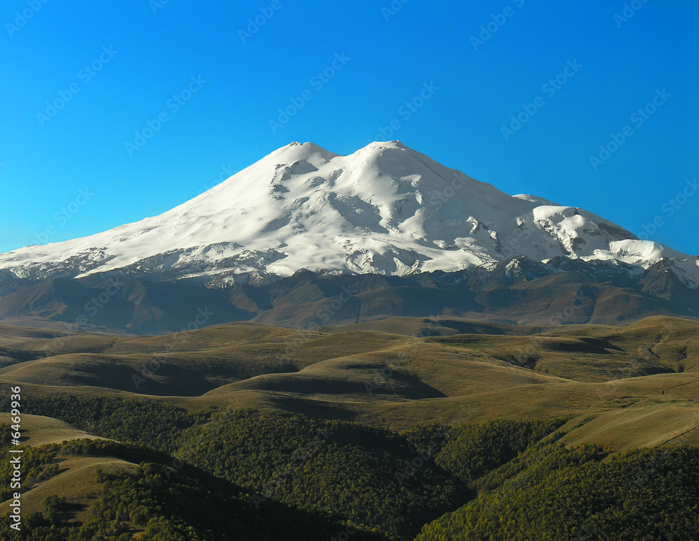 Snow-covered top of Elbrus on a background of the blue sky