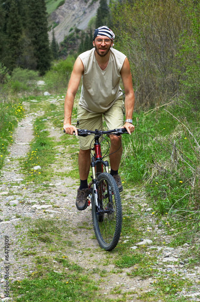 Fototapeta premium Mountain biker on old rural road in spring mountain