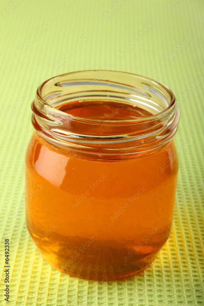 Honey in glass pot on green background Honey in glass pot on green background