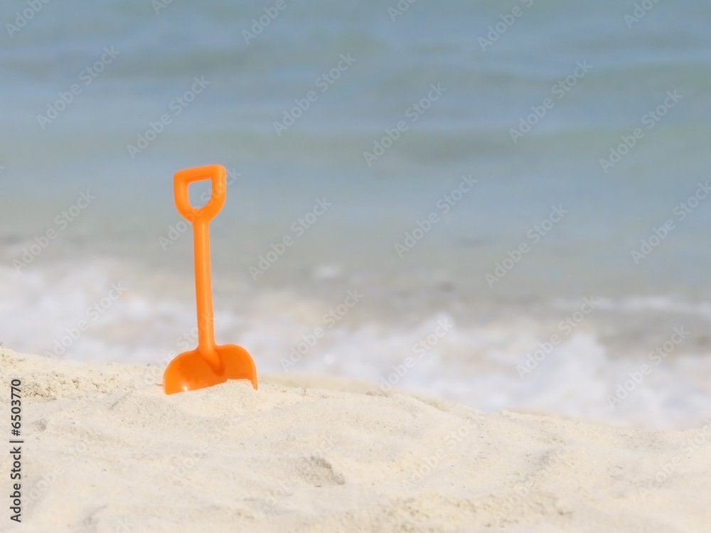 red plastic spade on the sunny tropical beach red plastic spade on the sunny tropical beach