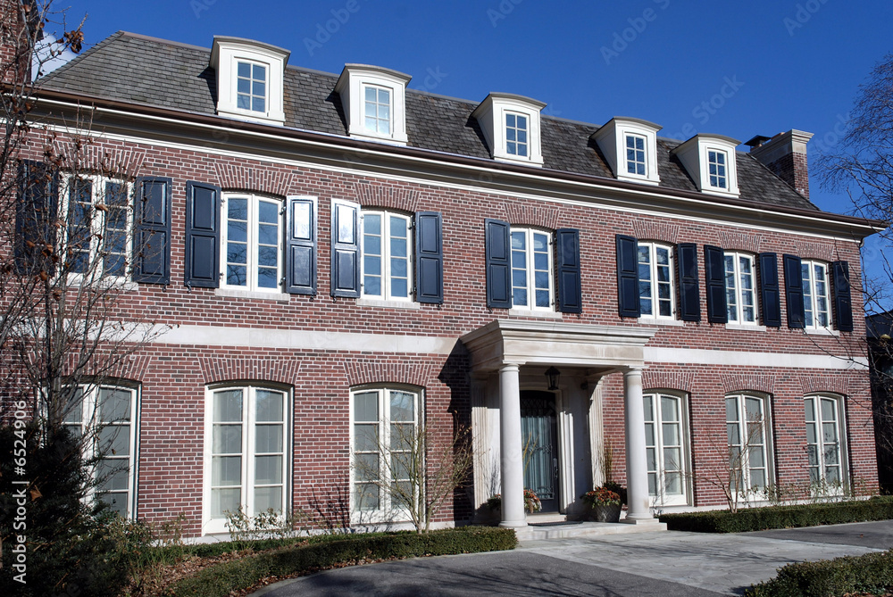 large brick house with portico and shutters