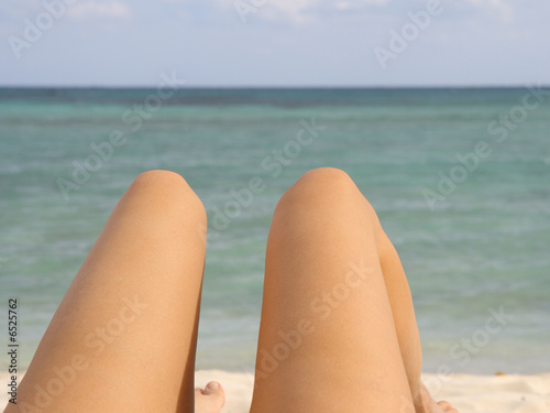 Woman on the beach. Tanned legs and the sea.