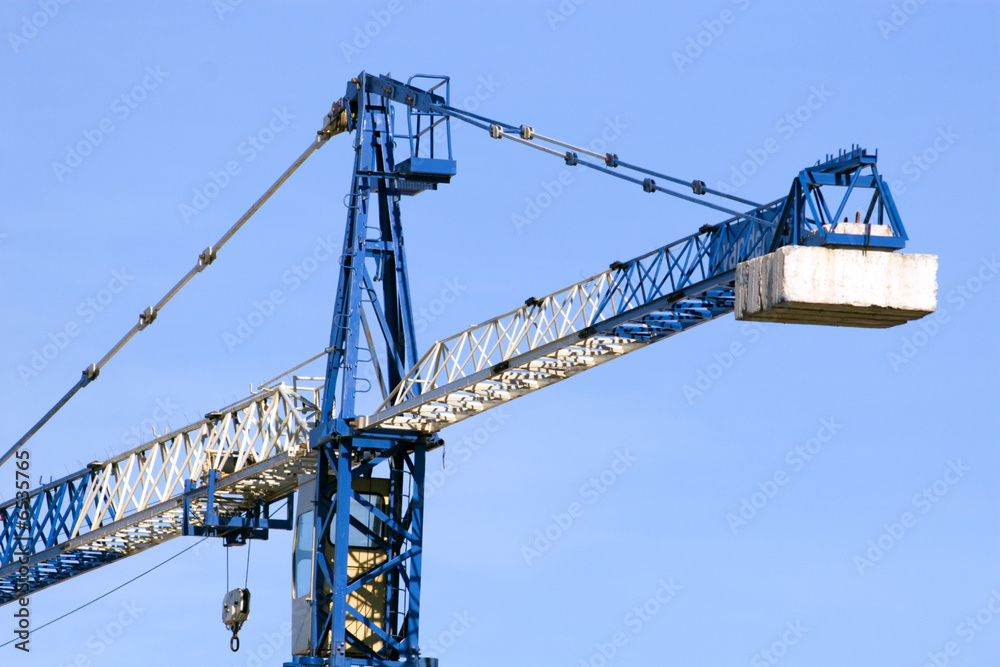 A blue and white crane at a construction site. A blue and white crane at a construction site.
