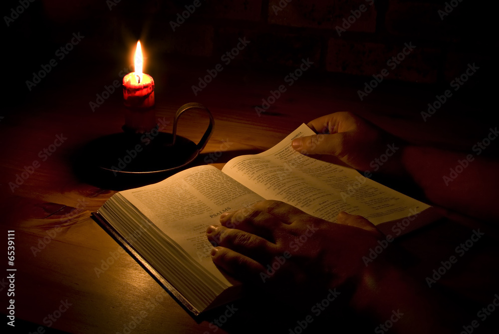 Obraz premium Reading the bible by candle light
