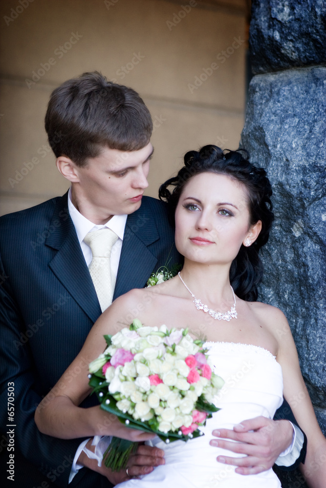 a portrait of the groom and the bride by the stone wall a portrait of the groom and the bride by the stone wall