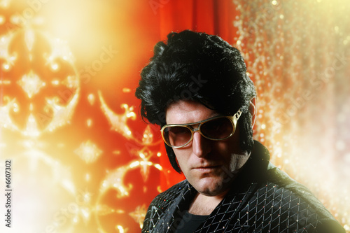 Elvis Presley impersonator over glowing background.