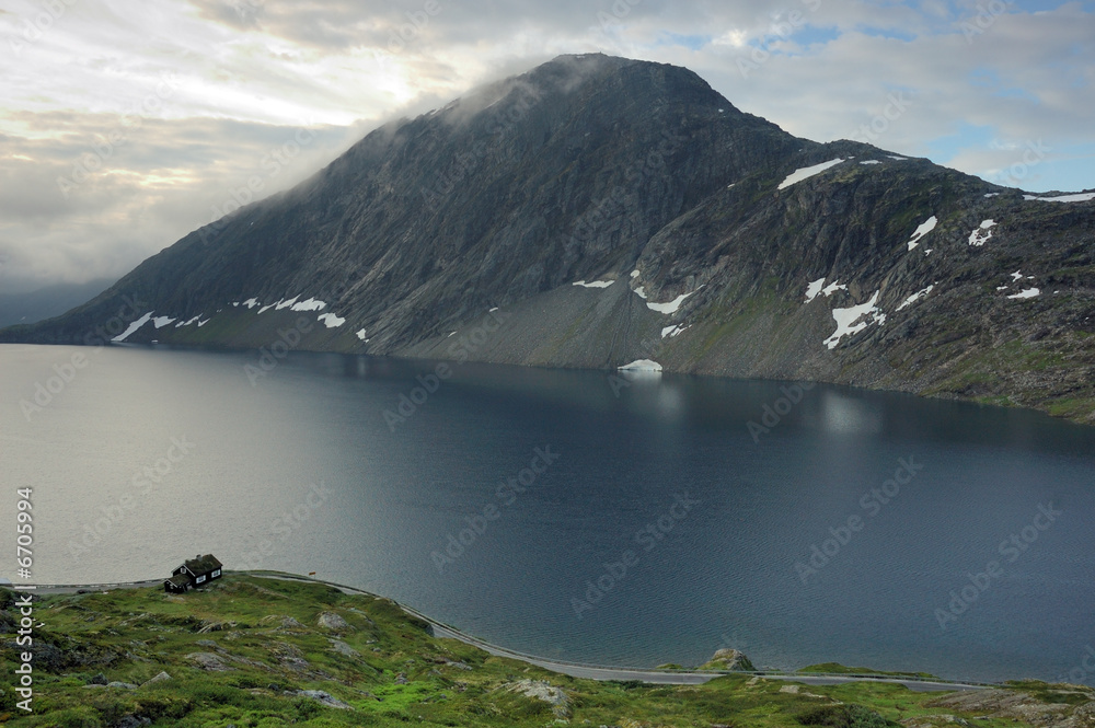 Obraz premium small cottage by the lake and mountain