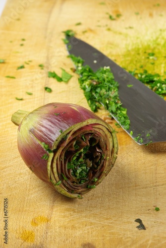 carciofo ripieno su tagliere con coltello e prezzemolo