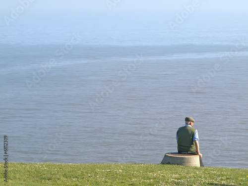 Anciano con gorra mirando al mar
