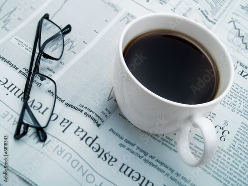 A cup of coffee, glasses and a newspaper