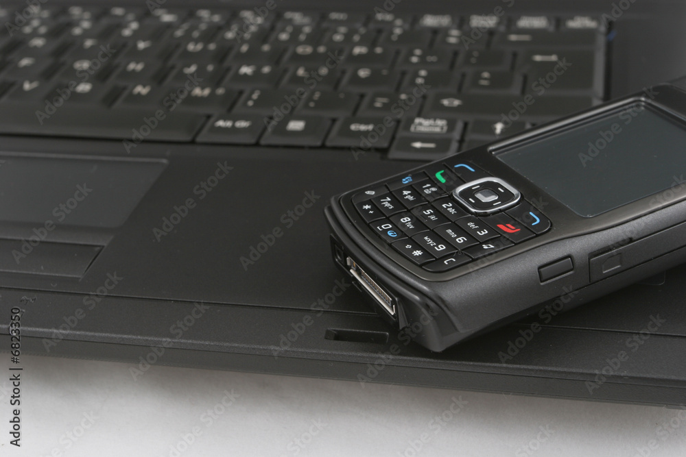 Cellphone isolated over laptop keyboard Cellphone isolated over laptop keyboard