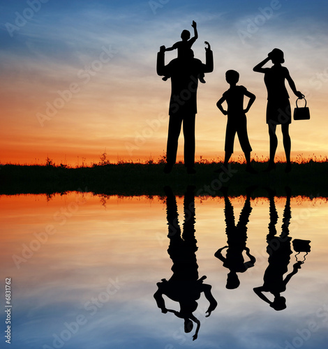 family silhouette on sunset sky. water