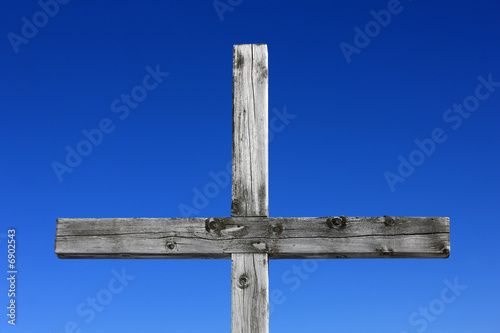 Holzkreuz vor blauem Himmelhintergrund