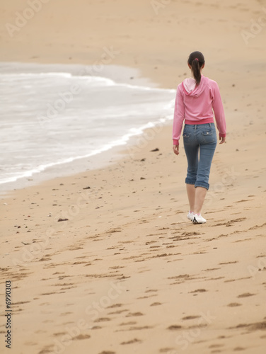 Adolescente caminando por la playa