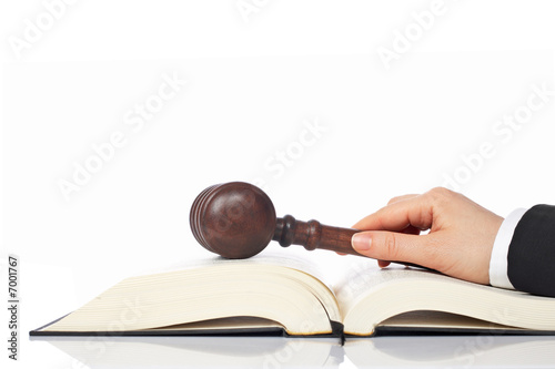 Holding a wooden gavel over the law book