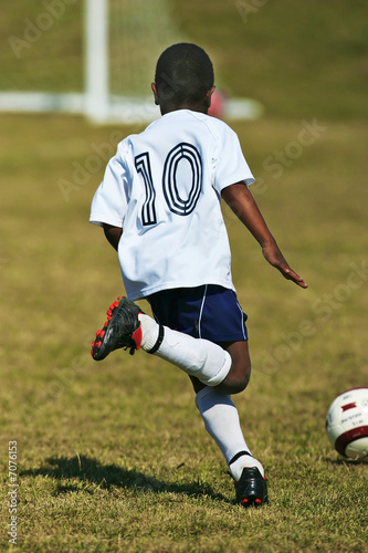 Boy youth soccer player dribbles ball to goal