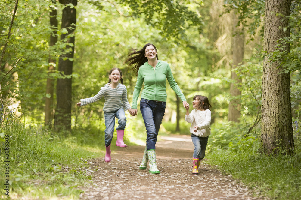 Mother running along woodland path with 2 childrren