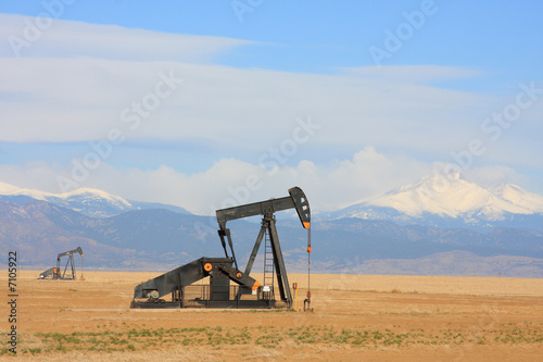 Pumpjack pumping oil, snow capped mountain background
