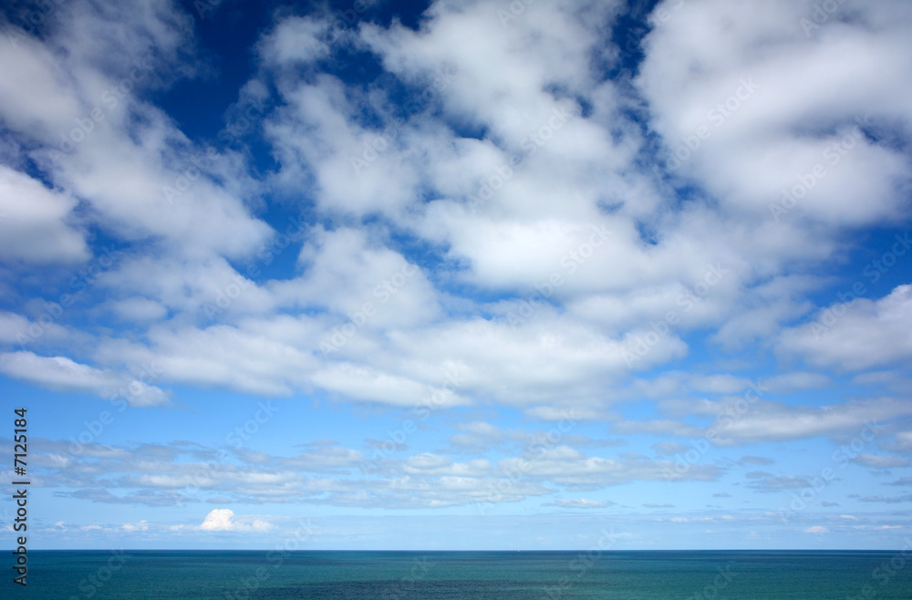 White clouds and blue sky high above the Atlantic ocean.