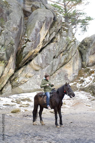 Girl on a horse on a background rocks