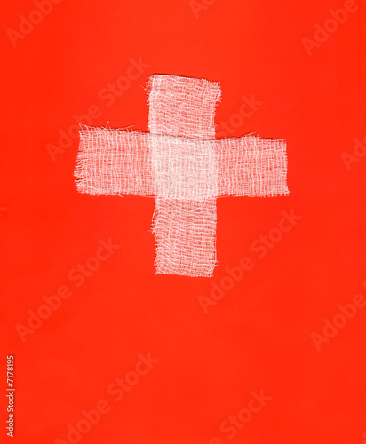 Two white bandages forming a cross on red background