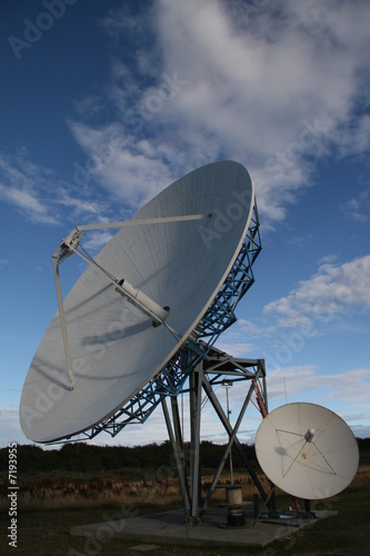Two satellite dishes in front of a blue sky