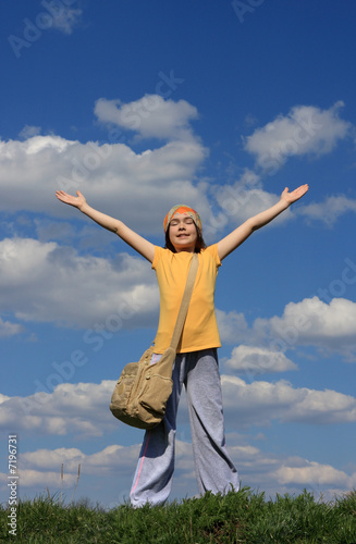 Girl holding hands up against blue sky 