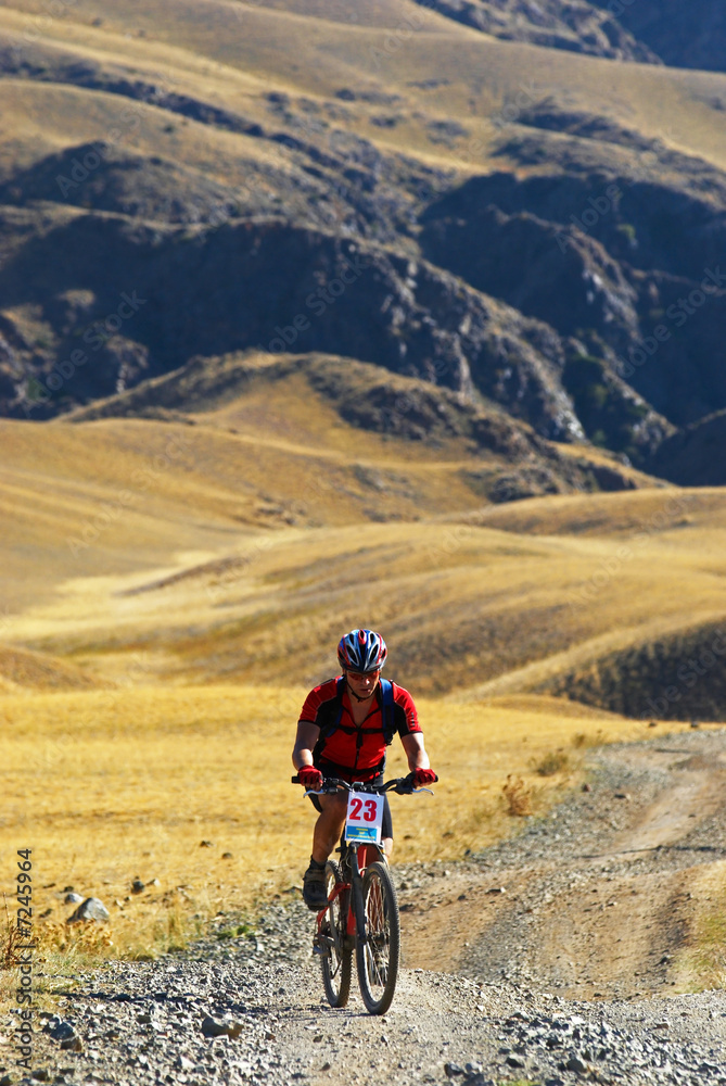 Mountain biker racing on old road in desert Mountain biker racing on old road in desert