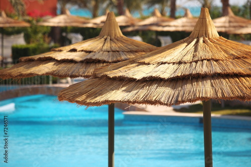 straw umbrellas on blue water.