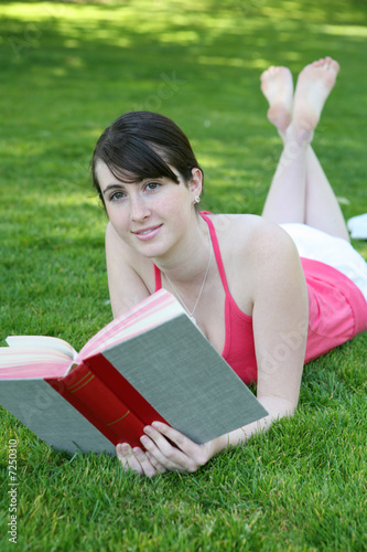 Cute Girl Reading a Book on the Grass Outside