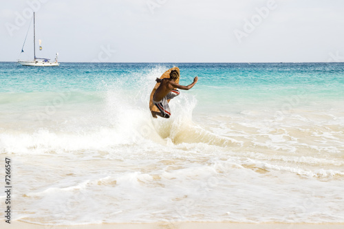man jumping wave on skimboard.
