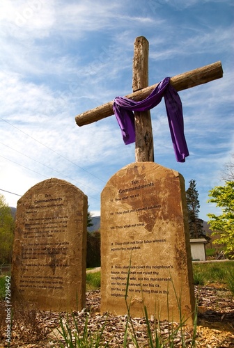 A cross with the ten commandments in stone in front of it.