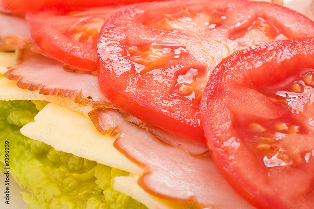 Lettuce, cheese, ham and tomatoes layered on a sandwich Lettuce, cheese, ham and tomatoes layered on a sandwich